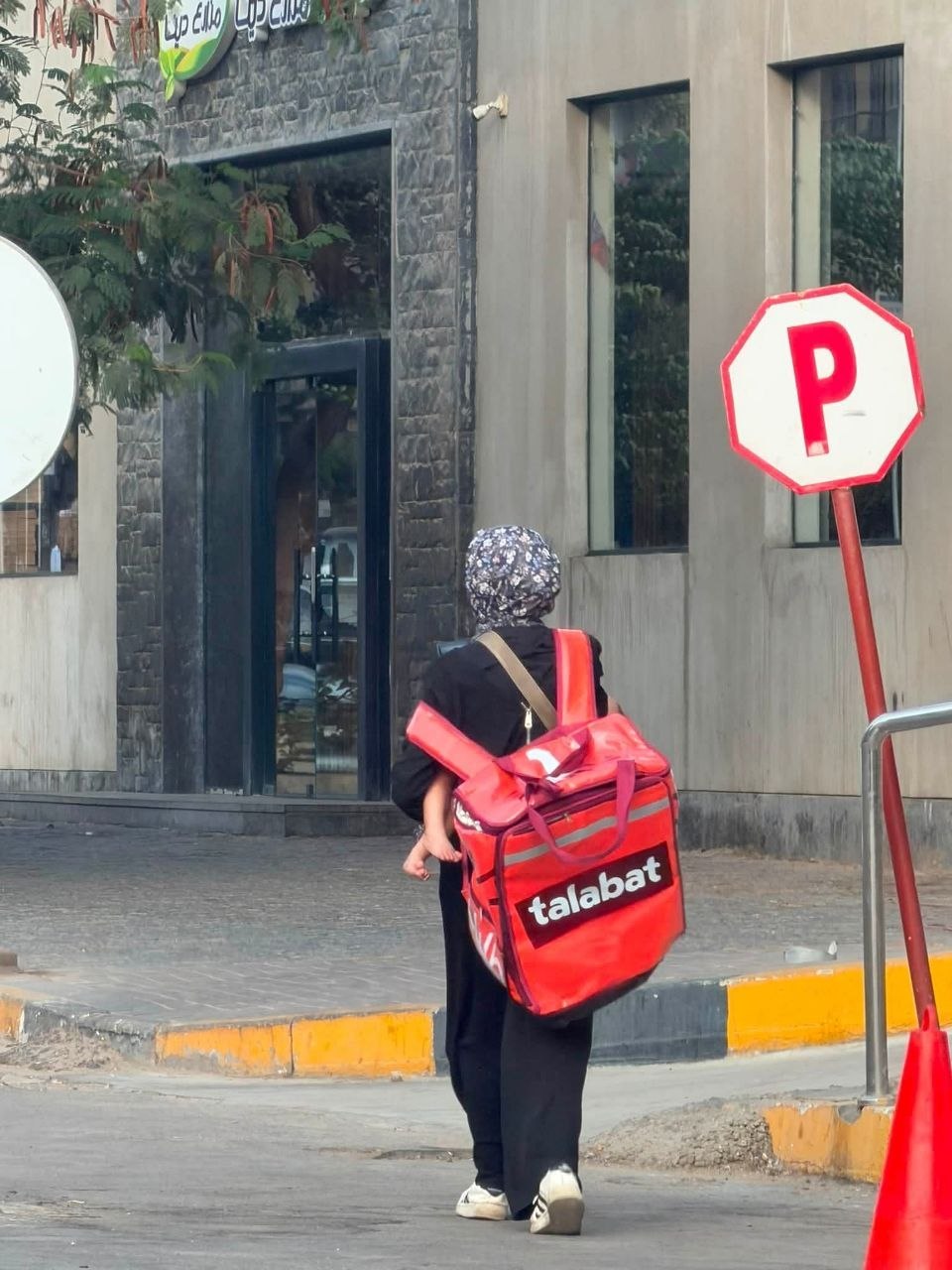 A rider carrying an oversized red delivery bag that hangs awkwardly off the body