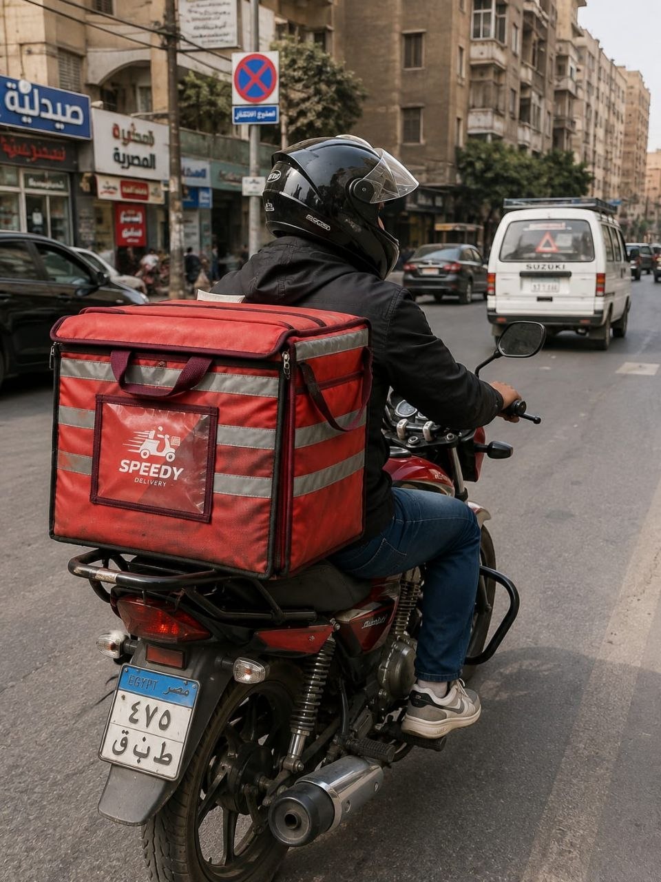 A motorcycle rider using a large rear-mounted delivery bag in traffic