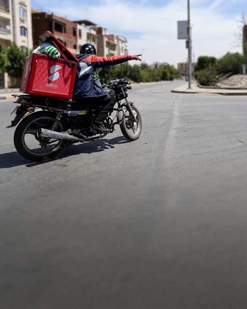 A rider carrying a tall, unstably mounted delivery bag on a motorcycle